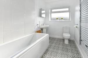 a white bathroom with a tub and a toilet at 20 Cae Du in Abersoch +15 photos