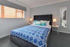 a bedroom with a blue and white bed and two lamps at 20 Cae Du in Abersoch