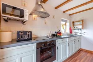 une cuisine avec des armoires blanches et un four à plaques de cuisson dans l'établissement Otter Cottage at West Ashridge, à Bideford 13 autres photos