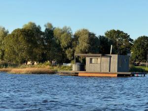 a tiny house on a dock on the water at Laivu nomas pirts in Ikšķile