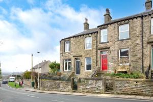 een stenen huis met een rode deur op een straat bij Jackdaw Cottage in Embsay