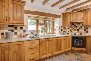 Una cocina con armarios de madera y un fregadero y una ventana. en Y Felin, en Machynlleth 7 fotos más