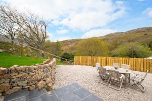 un patio avec une table et des chaises et un mur en pierre dans l'établissement Mor Mynydd, à Barmouth