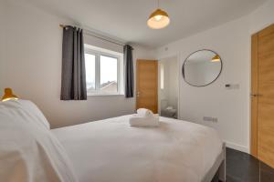 une chambre avec un grand lit blanc avec un miroir dans l'établissement Mor Mynydd, à Barmouth