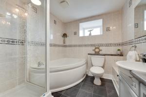 a bathroom with a tub and a toilet and a sink at Flora Belle Cottage in Sennen +16 photos