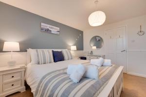 a bedroom with a large white bed with blue pillows at Flora Belle Cottage in Sennen