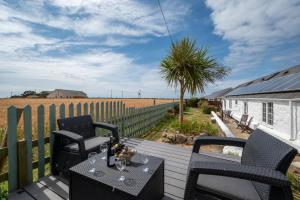 a patio with two chairs and a table and a fence at Flora Belle Cottage in Sennen