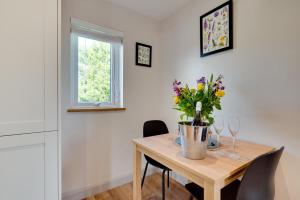 ein Esstisch mit einer Vase mit Blumen darauf in der Unterkunft Bryniau Pair Ucha Cottage in Gwytherin