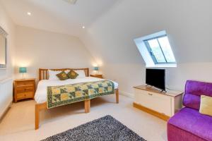 a bedroom with a bed and a purple chair at Pear Barn in Fylingdales
