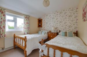 two beds in a bedroom with floral wallpaper at Y Bwthyn in Abererch