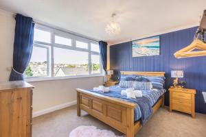 een slaapkamer met een bed met blauwe muren en een raam bij Soundwaves House in Bude