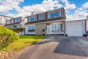 een groot huis met een garage en een oprit bij Soundwaves House in Bude