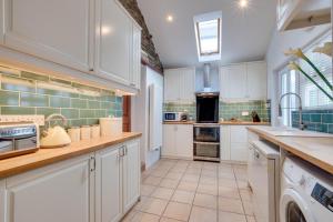 a kitchen with white cabinets and a tile floor at 2 Inglenook Cottages Croyde in Croyde