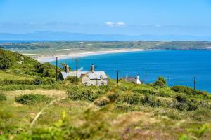a group of houses on a hill near a beach at St Aelrhiws Church in Rhiw