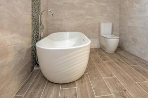 a bathroom with a white tub and a toilet at St Aelrhiws Church in Rhiw +21 photos