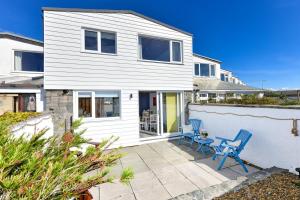 a white house with two blue chairs on a patio at 7 Marina Cottages in Pwllheli