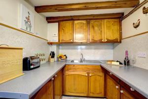 eine Küche mit Holzschränken und einer Spüle in der Unterkunft East Cottage in Thwaite + 7 Fotos