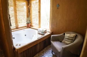 una vasca da bagno in una stanza con sedia e finestra di SutarHouse 