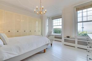ein weißes Schlafzimmer mit einem Bett und einem Kronleuchter in der Unterkunft Number 46 in Whitstable
