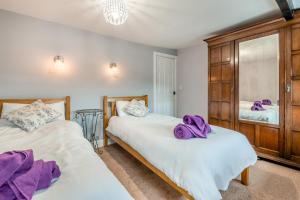 two beds in a bedroom with purple towels on them at 2 Ivy Terrace in Bradley