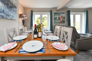 a dining room table with plates and wine glasses at 16 Maes Gwydryn in Abersoch