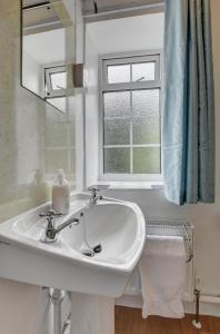 ein weißes Waschbecken im Bad mit Fenster in der Unterkunft Pusehill Cottage in Westward Ho