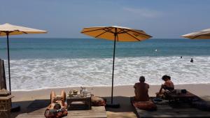 a group of people sitting on the beach under umbrellas at JJ Beach Resort & JJ Seafood in Ko Phayam