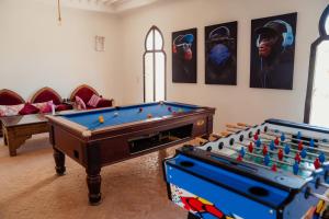 two pool tables in a room with portraits on the wall at DOMAINE DU DOUAR in Marrakesh