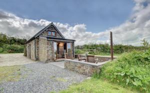 ein kleines Steinhaus mit einer Veranda und einer Terrasse in der Unterkunft Honeysuckle Cottage Welcombe in Welcombe