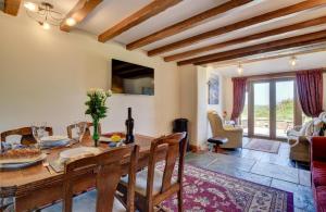 eine Küche und ein Wohnzimmer mit einem Holztisch in der Unterkunft Honeysuckle Cottage Welcombe in Welcombe