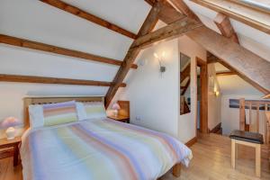 ein Schlafzimmer mit einem großen Bett mit Holzbalken in der Unterkunft Honeysuckle Cottage Welcombe in Welcombe