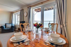 Un comedor con una mesa con vasos y flores. en Flat 24 Clifton Court, en Croyde