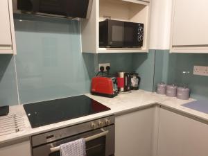 een keuken met witte kasten en een rood apparaat bij Cosy Family Flat in Elswick