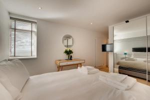 ein weißes Schlafzimmer mit einem Bett und einem Spiegel in der Unterkunft 3 Little Beach in Woolacombe