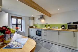 a kitchen with white cabinets and a wooden table at Cross Farm Cottage in Braunton