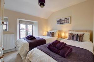 a bedroom with two beds with purple towels on them at Cross Farm Cottage in Braunton