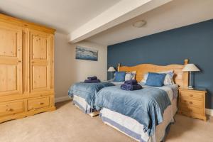 2 Betten in einem Schlafzimmer mit blauen Wänden in der Unterkunft Elterwater Apartment in Bowness-on-Windermere