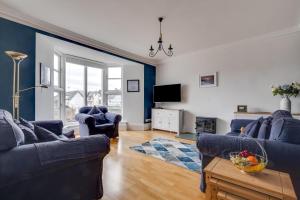 ein Wohnzimmer mit 2 blauen Sofas und einem TV in der Unterkunft Elterwater Apartment in Bowness-on-Windermere
