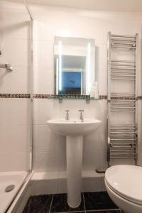 ein Badezimmer mit Waschbecken, Toilette und Spiegel in der Unterkunft Elterwater Apartment in Bowness-on-Windermere + 6 Fotos