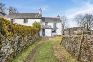 un vieux mur en pierre devant une maison blanche dans l'établissement The Cottage - Bellman House, à Crook