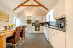 a kitchen with white cabinets and a wooden table at West Barn in Hodgeston
