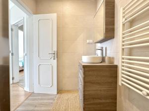 a bathroom with a sink and a mirror and a door at Quarteira Central Beach 5 by Homing in Cavacos +25 photos