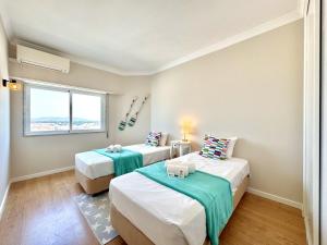 a room with two beds and a window at Quarteira Central Beach 5 by Homing in Cavacos