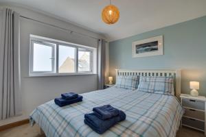 een slaapkamer met een bed met blauwe handdoeken erop bij Wills Cottage in Lower Boscaswell