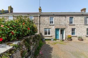 een oud stenen huis met een blauwe deur bij Wills Cottage in Lower Boscaswell