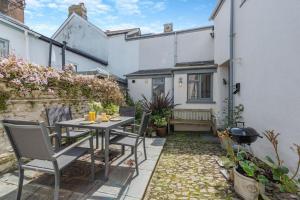 eine Terrasse mit Tisch und Stühlen vor einem Haus in der Unterkunft Annies Cottage - Appledore in Appledore