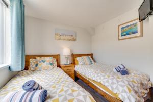 two twin beds in a room with a window at Pebbles Marazion in Marazion +8 photos