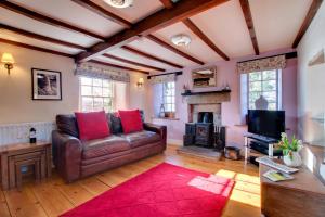 a living room with a leather couch and a fireplace at Rooks Cottage in Askrigg