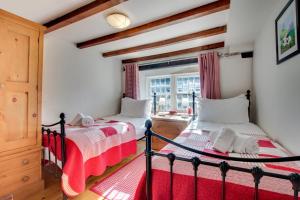two beds in a room with a window at Rooks Cottage in Askrigg