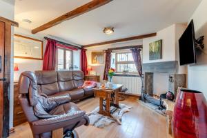 a living room with a leather couch and a fireplace at Annes Cottage in Lydbrook